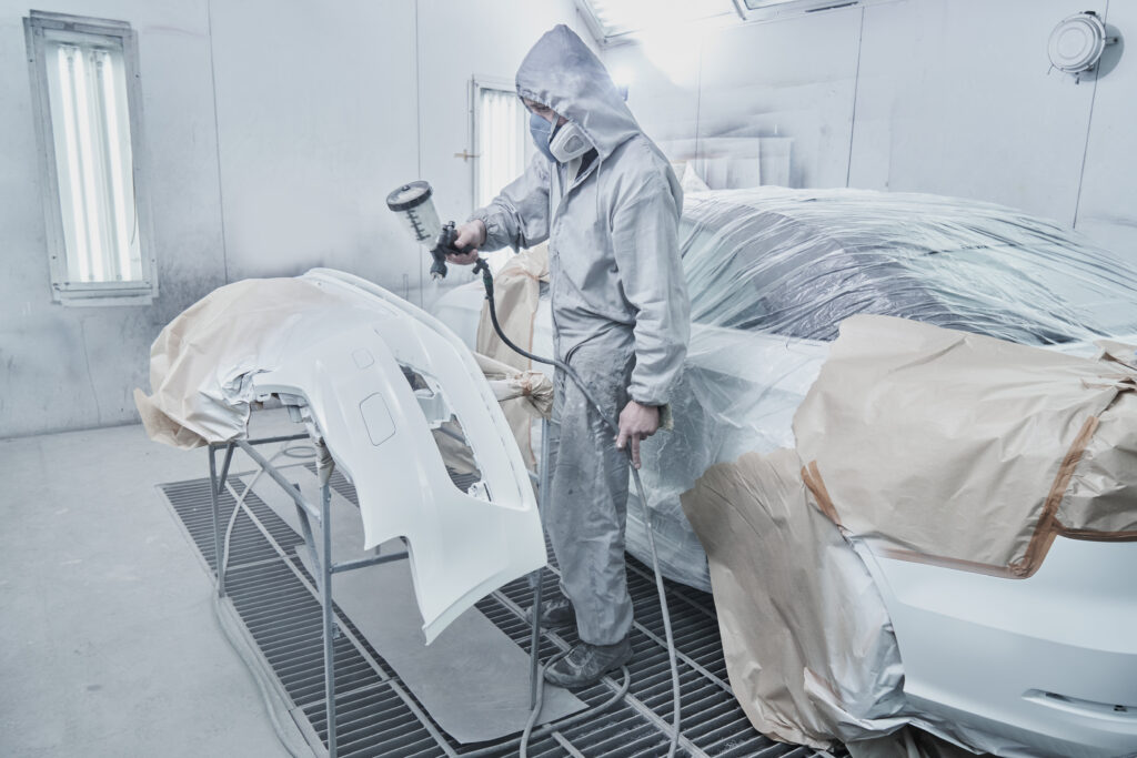 Car,Painting,And,Automobile,Repair,Service.,Auto,Mechanic,In,White Auto mechanic in white overalls paints car with spray brush in paint booth.