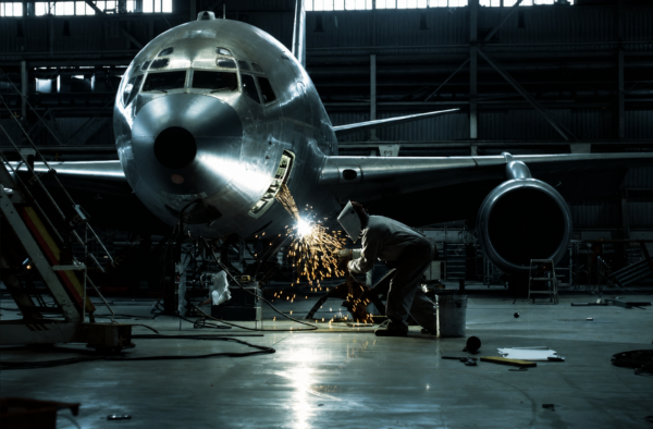 Aircraft Welding in Hangar Technician welding metal on an airplane nose inside a maintenance hangar.